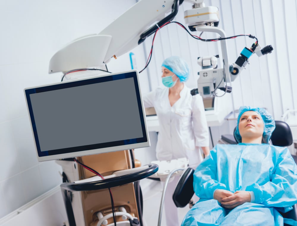 Woman and nurse preparing for LASIK surgery in an eye examination room.