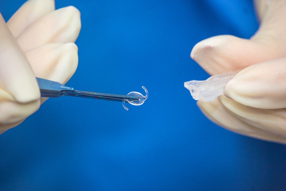 Close up of an ophthalmologist expertly handling an intraocular lens during lens replacement surgery.